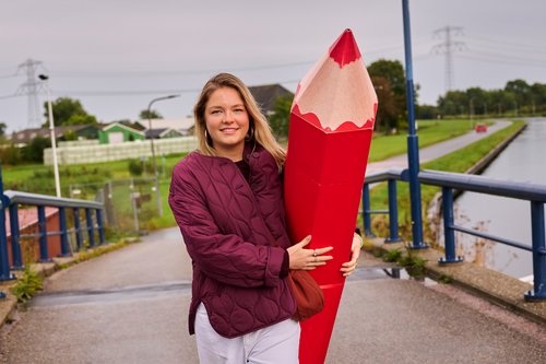 Jonge mevrouw met een grote rode potlood tussen haar handen.