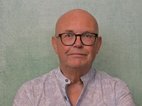 Jim Galesloot. Jim draagt een blouse waarvan de bovenste 2 knopen los zitten. Hij is kaal en draagt een bril.
