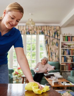 Schoonmaakster die helpt bij een oudere vrouw in huis