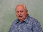 Gerrit Worst. Hij heeft grijs haar en een blauwe blouse met bloemen erop.