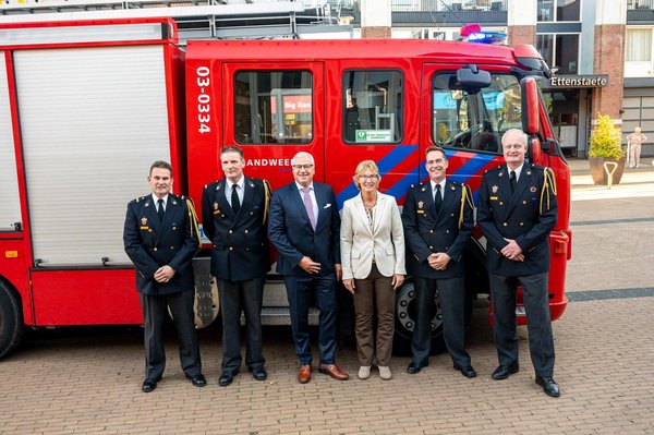 Burgemeester Jan Zwiers staat met de brandweer voor een brandweerauto