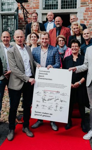 De wethouders van 12 gemeenten staan naast een bord met daarop al hun handtekeningen