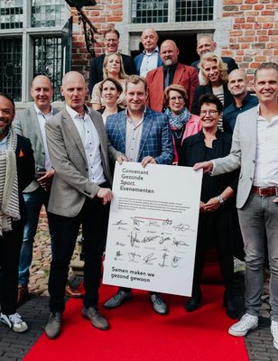 De wethouders van 12 gemeenten staan naast een bord met daarop al hun handtekeningen