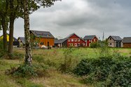 Dri huizen naast elkaar op Lievingerveld. De 1 donkerbruin houtkleurig, 1 huis is rood en 1 huis heeft een beige kleur.