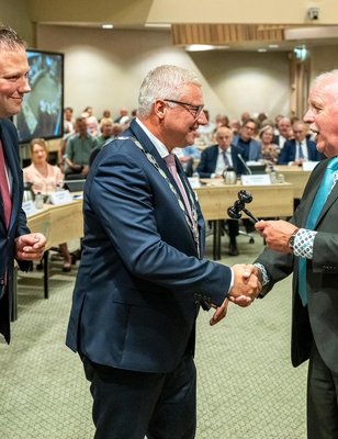 Burgemeester Jan Zwiers wordt gefeliciteerd door Jan Beugel. Wethouder Dennis Bouwman kijkt toe.