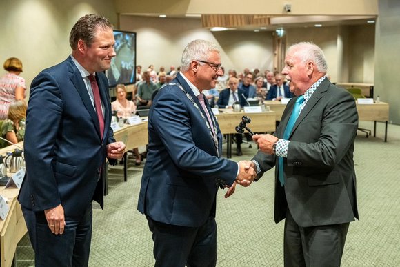 Burgemeester Jan Zwiers wordt gefeliciteerd door Jan Beugel. Wethouder Dennis Bouwman kijkt toe.